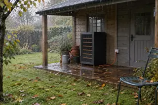 Une cave à vin sous l'auvent d'un abri de jardin sous la pluie, feuilles mortes, rallonge électrique