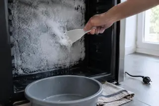 Gros plan sur une paroi arrière givrée de cave à vin, une spatule en plastique et une bassine au sol
