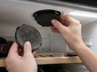 Gros plan sur des mains remplaçant le petit filtre à charbon rond au plafond d'une cave à vin, l'ancien filtre noirci