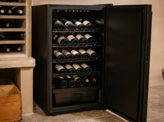 Open Climadiff Avi77 electric wine cellar filled with organized wine bottles in a modern home interior, highlighting storage, humidity basin, and anti-vibration features.