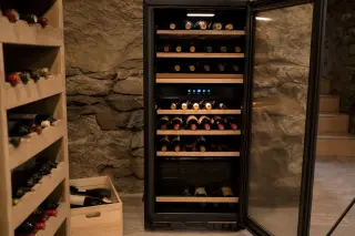 Modern electric wine aging cabinet open in a stylish apartment, showcasing neatly arranged bottles, LED lighting, and digital controls for temperature and humidity.
