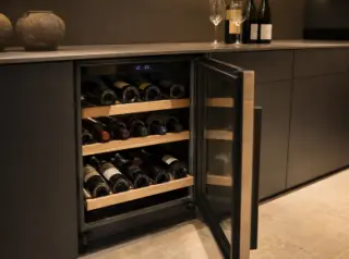 Built-in wine cellar in a modern kitchen with bottles stored on wooden shelves and digital controls visible.