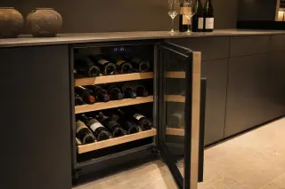 Built-in wine cellar in a modern kitchen with bottles stored on wooden shelves and digital controls visible.