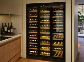 Built-in multi-zone wine cellar in a modern kitchen, glass front showing three zones with organized wine bottles and digital controls.